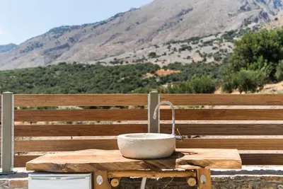 a stone sink on a wooden table in front of a bench at Villa Olvía in Sfakiá