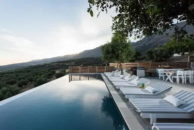 a pool with lounge chairs and a table and water at Villa Olvía in Sfakiá