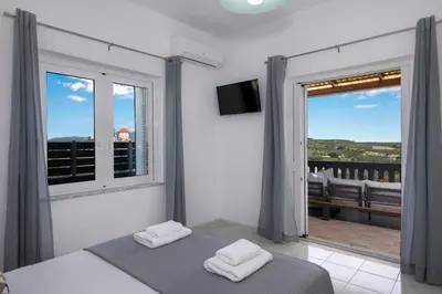 a bedroom with a bed and a large window at Marakas Winery Family House in Xamoudhokhórion