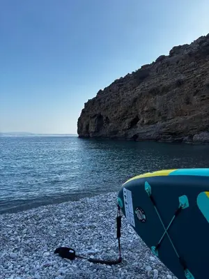 a surfboard sitting on a rocky beach next to the water at Traditional Villa with pool in Sfakia in Ímbros