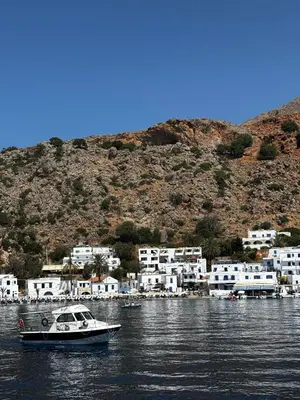 a boat in the water in front of a village at Traditional Villa with pool in Sfakia in Ímbros