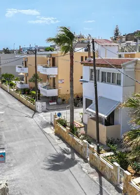 an empty street in front of buildings with a palm tree at Kydonia apartments in Plataniás