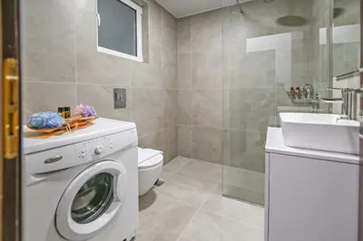 a bathroom with a washing machine and a sink at A & G Apartments in Kolymvari
