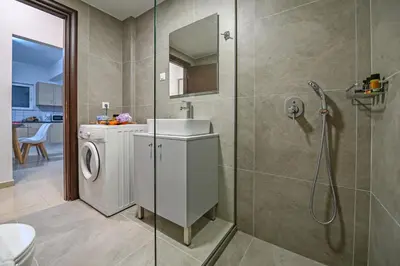 a bathroom with a washing machine and a sink at A & G Apartments in Kolymvari