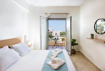 a white bedroom with a bed and a balcony at Kds Overlooking Chania in Chania Town