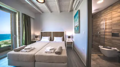 a bedroom with a large bed and a bath tub and a bathroom at Nafsika Xenia - Alkinoos Villa in Plátanos