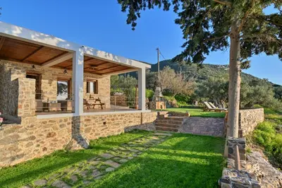 an external view of a stone house with a patio at Metochi Seaview Holiday House in Ayía Paraskeví