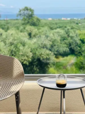 a table and a chair on a balcony with a view at Meliora Suites in Drapaniás