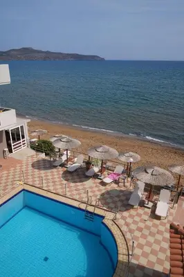 a swimming pool next to a beach with umbrellas at Cozy Corner VS Beachfront in Stalos