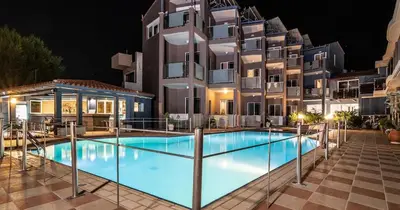 a swimming pool in front of a building at night at Cozy Corner VS Beachfront in Stalos