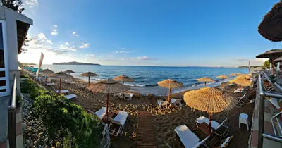 a beach with umbrellas and chairs and the ocean at Cozy Corner VS Beachfront in Stalos
