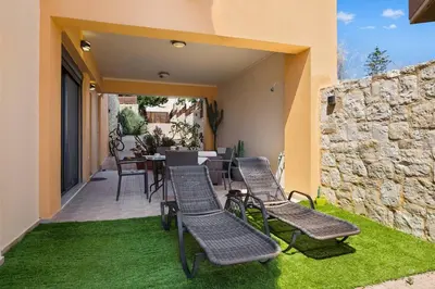 a patio with chairs and a table and a stone wall at Private apartment in Kalamaki, Chania in Galatás