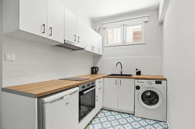 a kitchen with white cabinets and a washer and dryer at Nisos apartments, Chania center in Chania Town