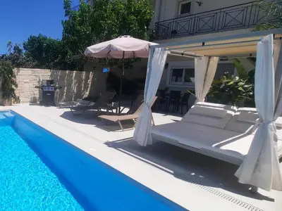a pool with chairs and an umbrella next to a house at Amare suite in Perivólia
