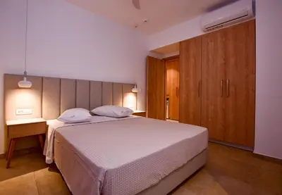 a bedroom with a white bed and a wooden cabinet at Rosemary Apartments in Palaiochóra