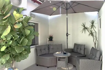 a patio with two couches and a table and an umbrella at Stamatias Home, fully equipped cottage 5 minutes from the sea in Chania Town