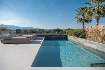 a swimming pool with blue water and palm trees at Fivi Villa, with Heated Pool & SeaViews, By ThinkVilla in Tavronitis