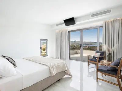 a white bedroom with a bed and a balcony at Fivi Villa, with Heated Pool & SeaViews, By ThinkVilla in Tavronitis