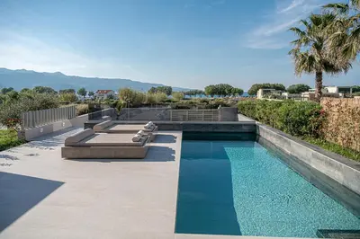 a swimming pool with two loungers on a patio at Fivi Villa, with Heated Pool & SeaViews, By ThinkVilla in Tavronitis