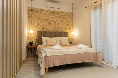 a bedroom with a large bed with a stone wall at Casa Dionysia - New Lux 2Br with Jacuzzi near Maleme Beach in Maleme