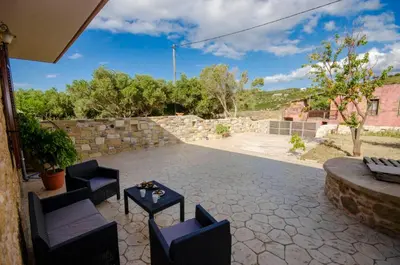 a patio with chairs and a table and a stone wall at Metochi Traditional House in Chania Town