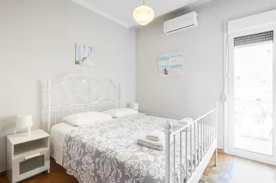 a white bedroom with a white bed and a window at Angelina House in Chania Town
