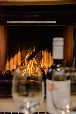 a bottle of wine and a glass in front of a fireplace at Alonion Apartments in Yerakianá