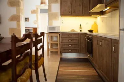 a kitchen with wooden cabinets and a counter top at Cretan cottage of 1900 with beautiful olive yard in Kissamos