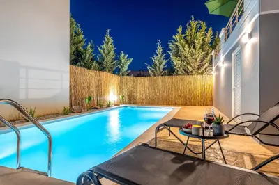 a swimming pool in the backyard of a house at night at Emma Hills Villa in Korakiaí