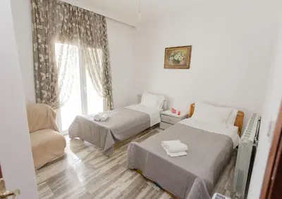 a room with two beds and a chair and a window at Arias'-Welcoming Guest House in Kounoupidhianá