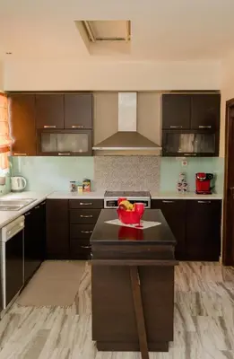 a kitchen with brown cabinets and a bowl of fruit on a table at Arias'-Welcoming Guest House in Kounoupidhianá