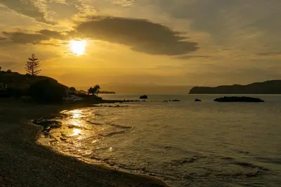 a sunset on a beach with the sun setting at Seize the seas in Kalamaki Chanion