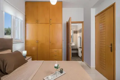 a bedroom with a bed and wooden cabinets and a bathroom at Olive Tree Villa in Chania Town