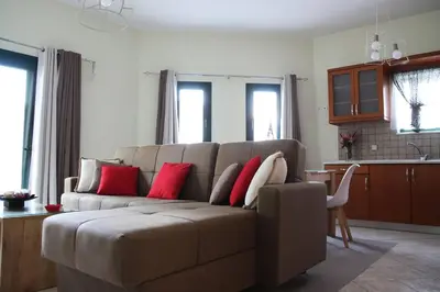 a living room with a brown couch with red pillows at Anna Kavros appartment in Chania Town
