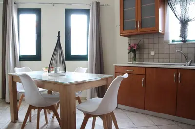 a kitchen with a wooden table and white chairs at Anna Kavros appartment in Chania Town