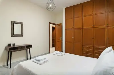 a bedroom with a bed with wooden cabinets and a mirror at Villa Androniki in Souda