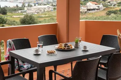 a table with a plate of food on a balcony at Villa Androniki in Souda