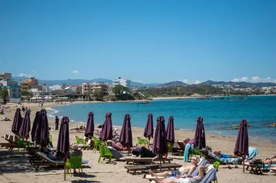 a beach with people sitting in chairs and umbrellas at Eva's Residence, Family Apartment in Chania Town