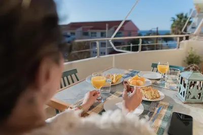 a woman sitting at a table with food and orange juice at Dejaview cozy apartment by 8essentially in Chania Town