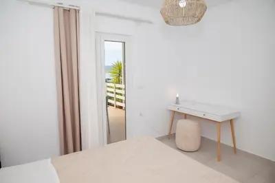a white bedroom with a table and a mirror at Elia Apartments in Falasarna