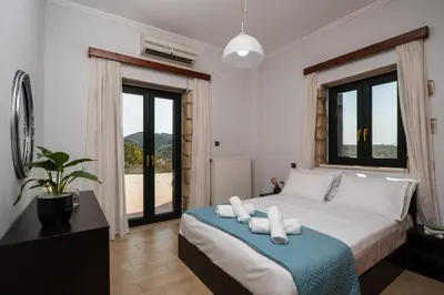 a bedroom with a bed and a large window at Agnadia Villa in Stalos