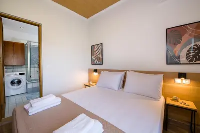 a bedroom with a white bed and a washing machine at G & E Apartment in Kissamos