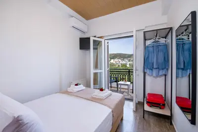 a white bedroom with a bed and a balcony at G & E Apartment in Kissamos