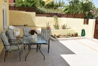 a patio with a table and chairs and a garden at Eleni's Σπίτι μπροστά στη θάλασσα in Daratso