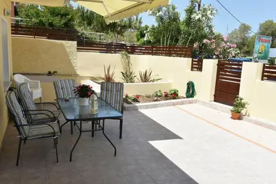 a patio with a table and chairs and a fence at Eleni's Σπίτι μπροστά στη θάλασσα in Daratso