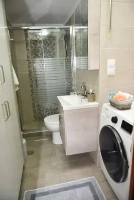 a bathroom with a toilet sink and a washing machine at Eleni's Σπίτι μπροστά στη θάλασσα in Daratso