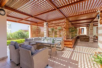 a patio with a table and chairs under a wooden pergola at Gold Crest Home in Drapanias beach, Nopigia in Kissamos