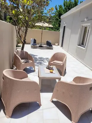 a patio with chairs and tables and an umbrella at Hygge Home Chania in Chania Town