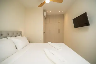 a bedroom with a white bed with a flat screen tv at Cozy Spot II near the beach in Ayiá